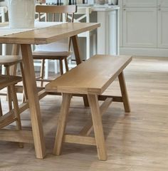 a wooden table with chairs and a vase on top of it in the middle of a kitchen