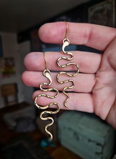 a person holding some kind of gold snake earrings