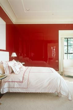 a bedroom with red walls and white bedding