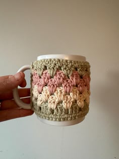 a hand holding a coffee cup with crochet on it