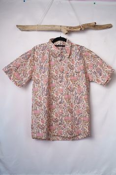 Découvrez notre chemise à manches courtes, faite main avec soin. Confectionnée en 100% coton, elle est légère et agréable à porter. Ses motifs bariolés et sa coupe classique lui donnent une allure à la fois décontractée et élégante. Le devant est orné de boutons en nacre blancs, ainsi que d'une poche. Pour préserver la qualité de votre chemise, nous recommandons un lavage à 30oC maximum lors de la première utilisation, de préférence séparément.  Veuillez noter que chaque pièce est unique en rais Pink Cotton Short Sleeve Shirt, White Cotton Camp Shirt With Floral Print, Summer Block Print Short Sleeve Top, Summer Short Sleeve Top With Block Print, Pattern Print Cotton Short Sleeve Top, Multicolor Floral Print Short Sleeve Camp Shirt, Patterned Cotton Camp Shirt With Short Sleeves, Cotton Short Sleeve Top With Pattern Prints, Cotton Tops With Pattern Prints And Short Sleeves