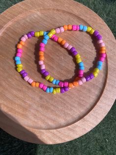 a wooden tray with two bracelets on it and one bead in the middle