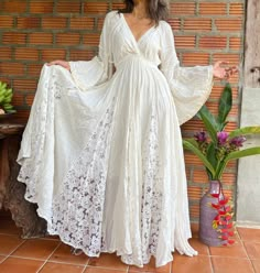 a woman wearing a white dress standing in front of a brick wall