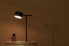 a black lamp sitting on top of a counter next to a bottle and soap dispenser