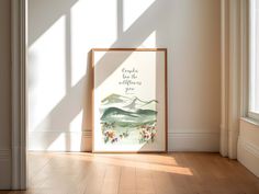 an empty room with a framed poster on the floor and sunlight coming through the window