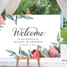 a welcome sign with flowers and greenery on it