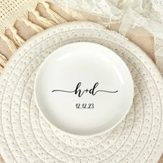 a white plate with the word h & d on it next to a lace doily