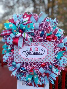 a colorful christmas wreath on top of a red fence