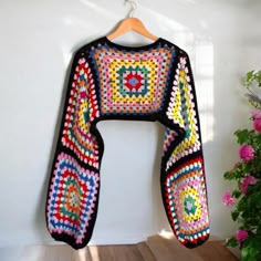 a colorful crocheted sweater hanging on a wall