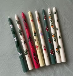 five candles lined up next to each other in different designs and colors, all decorated with christmas decorations