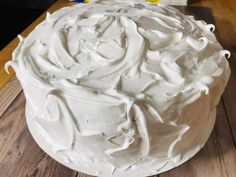 a white frosted cake sitting on top of a wooden table