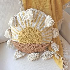 a white chair with a yellow blanket and some tassels on top of it