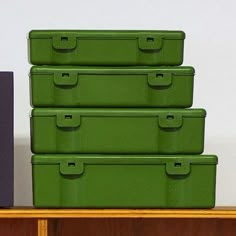 four green storage boxes sitting on top of a wooden shelf next to a purple box