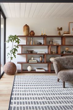 a living room filled with lots of furniture and shelves full of vases on top of them