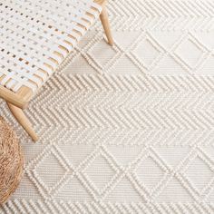 a woven chair and wicker basket sit on the floor in front of a white rug