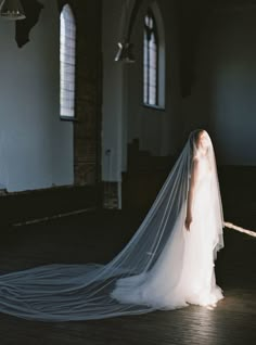 a woman in a wedding dress is standing on the floor with her veil over her head