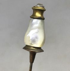 an old fashioned lamp with a white glass shade on it's top and a gold base