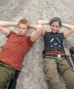 two people laying on the ground with their hands behind their heads