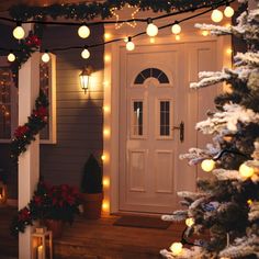 christmas lights are hanging on the front door of a house with trees and potted plants