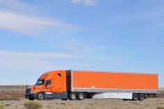 an orange semi truck is parked in the desert