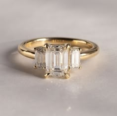 three stone engagement ring in yellow gold with baguettes on the sides and side stones