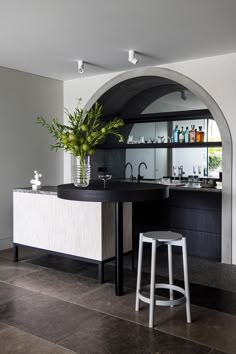 a modern kitchen with an arch in the wall and bar stools at the counter