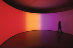 a person standing in front of a rainbow colored wall with the light coming through it