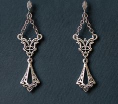 Gothic Chain Chandelier earrings, featuring ornate antique silver filigree, two sets of chains, and ornate filigree charms. Perfect for those who adore the Gothic Victorian aesthetic, these earrings add a touch of elegance and mystery to any outfit. Features: Length: 2.75 inches, excluding the lever back closure, 3.5 inches with the lever backs Closure: Stainless steel lever backs These beautiful earrings are the perfect accessory for enhancing your Gothic Victorian look with their intricate des Elegant Oxidized Chandelier Earrings For Weddings, Antique Silver Chandelier Earrings For Formal Occasions, Ornate Silver Chandelier Earrings Nickel Free, Antique Silver Chandelier Earrings As Gift, Antique Silver Chandelier Earrings For Gift, Silver Dangle Chandelier Earrings With Intricate Design, Vintage Style Chandelier Earrings With Intricate Dangle Design, Ornate Silver Chandelier Earrings As Gift, Victorian Filigree Chandelier Earrings As Gift