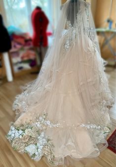 a wedding dress is on display in a room with wooden flooring and white flowers