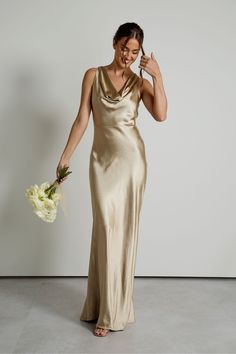 a woman in a gold dress holding a bouquet and posing for the camera with her hand on her face