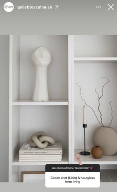 a white shelf with books, vases and other items on it's shelves