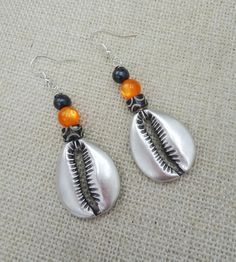 The silver plated cowrie is beaded with carved and glass beads. The earrings will come with back stoppers. If you have any questions please feel free to contact us at anytime. All shipping options are available. All items will be shipped out Monday through Friday. Receipts will be emailed out for immediate access. All items will be shipped out carefully and every shipment can be made with extra insurance upon request. All other concerns and details can be found in our policy section. Our goal is for your 100% satisfaction. If you would like to make a large order please contact us for a coupon code. Our products are not intended for babies or children as we use small pieces, wires and beads. These can be dangerous to them when unsupervised. Gift boxes and gift messages are available for you Beach Beaded Metal Earrings, Handmade Metal Beaded Earrings For Beach, Metal Beaded Earrings For Beach, Silver Beaded Earrings With Dangling Beads For Festival, Silver Metal Beach Jewelry, Silver Beaded Jewelry For Beach, Silver Metal Jewelry For The Beach, Beaded Metal Drop Earrings For Beach, Metal Beaded Drop Earrings For Beach