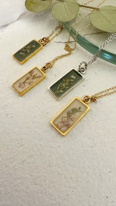 "Beautiful necklace made with delicate flower . Delicately pressed and preserved real leafs and florals necklace in silver or gold  some of the flowers used  caspia  wheat grass  Berry  In a  rectangle or arrow open bezel shape with real 24k gold plated chain or sterling silver , 18\" inch delicate chain  Delicate and stunning ...the perfect gift. Meaningful gift for her  Sure will make you smile. Please note every item is handmade just for you and for that reason we do not accept returns  Any question please let us know.    Nature is unique and one of a kind we select very carefully every flower and every petal and imperfections is what makes nature unique and more beautiful" Elegant Pressed Flower Necklaces As A Gift For Her, Elegant Necklaces With Pressed Flowers For Her, Elegant Pressed Flowers Necklace As Gift For Her, Botanical Jewelry With Pressed Flowers, Flower Charm Necklaces With Pressed Flowers, Vintage Gold Necklace With Pressed Flowers, Minimalist Silver Necklace With Pressed Flowers, Dry Flower Jewelry, Dried Flower Necklace