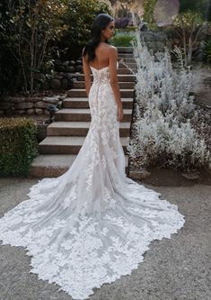 a woman standing in front of some steps wearing a wedding dress with an open back