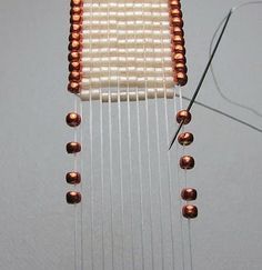 a close up of a weaving machine with copper beads on it's end and thread coming from the needle