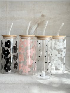 four glass cups with straws are lined up in a row and decorated with polka dots