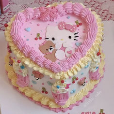 a heart shaped cake with hello kitty decorations on the top and sides, sitting on a table