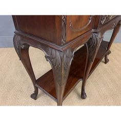 an antique wooden sideboard with carvings on the top and bottom, sitting on a carpeted floor