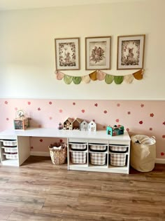 a room with pink walls and wooden flooring, two pictures on the wall above it