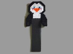 a black and white beaded brooch with an orange beak on it's head