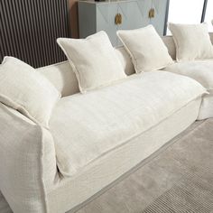 a white couch sitting on top of a carpeted floor next to a wooden cabinet