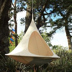 a hanging chair in the middle of some trees