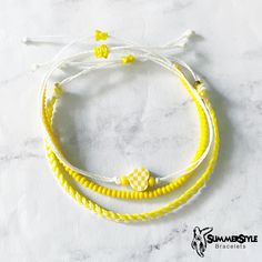 three bracelets with yellow and white beads on them sitting on a marble counter top