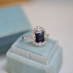 an engagement ring with a large blue stone surrounded by small white diamonds in a box