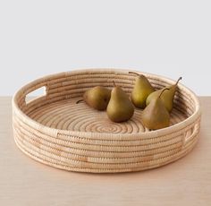 three pears in a woven basket on a table