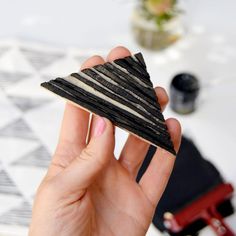 a woman holding up a small piece of black and white material on top of a table