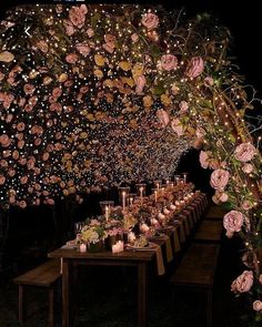 a long table covered in lots of flowers and lit up with candles on top of it