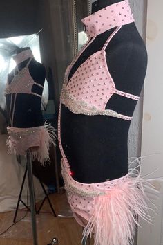 a mannequin with pink feathers on it's back in front of a mirror