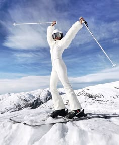 a person on skis standing in the snow with their arms up and hands out