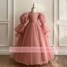 a pink dress on a mannequin stand in front of a white wall and wooden floor